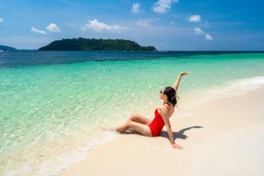 Young woman traveler relaxing and enjoying at beautiful tropical white sand beach, Summer vacation